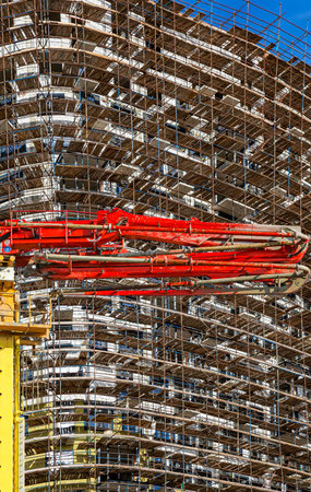 Construction concrete pump (pump truck) with multi-storey building under construction with...