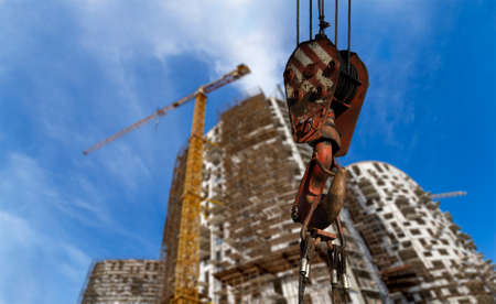 Construction crane hook with multi-storey building under construction with scaffolding (new residential complex) on the background, Moscow, Russiaの写真素材