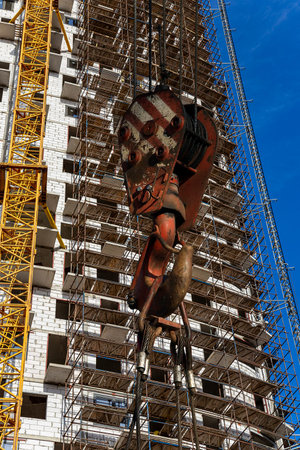 Construction crane hook with multi-storey building under construction with scaffolding (new...