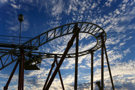 Attraction roller-coaster (switchback) on the background of the cloudy skyの写真素材