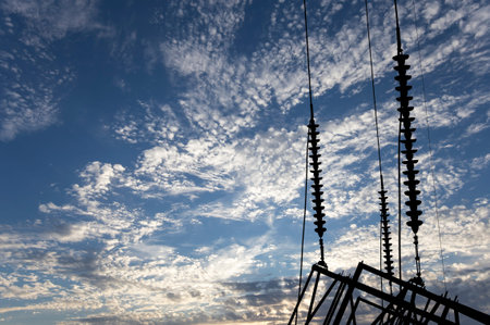 Electricity pylon (high voltage power line), black contour, on the background of the cloudy sky