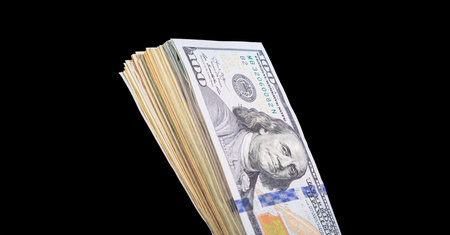 One hundred dollar bills, on a black background