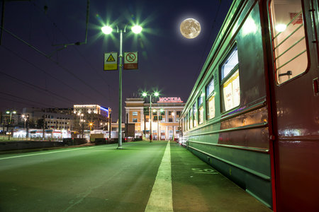 Train on Moscow passenger platform (Savelovsky railway station) with the super moon -- is one of the nine main railway stations in Moscow, Russia (at night)の写真素材