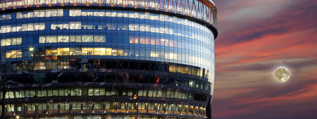 modern office building with big windows at night with the super moon, in windows light shines....
