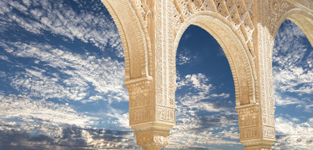 Arches in Islam (Moorish) style (against the background of a beautiful sky with clouds) in Alhambra, Granada, Spainの写真素材