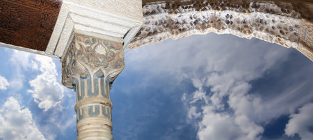 Arches in Islam (Moorish) style (against the background of a beautiful sky with clouds) in Alhambra,...