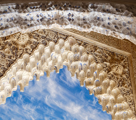 Arches in Islam (Moorish) style (against the background of a beautiful sky with clouds) in Alhambra,...