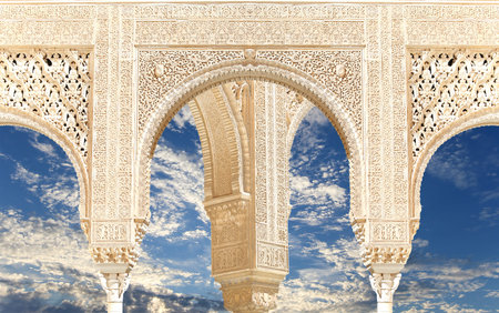 Arches in Islam (Moorish) style (against the background of a beautiful sky with clouds) in Alhambra,...