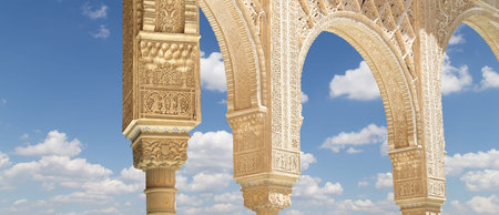Arches in Islam (Moorish) style (against the background of a beautiful sky with clouds) in Alhambra,...