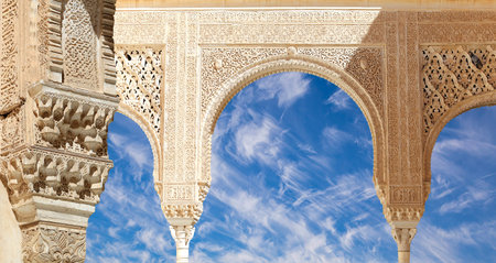 Arches in Islam (Moorish) style (against the background of a beautiful sky with clouds) in Alhambra,...