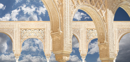 Arches in Islam (Moorish) style (against the background of a beautiful sky with clouds) in Alhambra,...