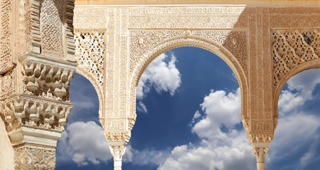 Arches in Islam (Moorish) style (against the background of a beautiful sky with clouds) in Alhambra,...