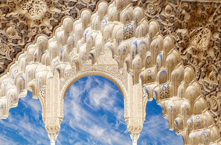 Arches in Islam (Moorish) style (against the background of a beautiful sky with clouds) in Alhambra,...