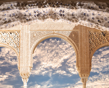 Arches in Islam (Moorish) style (against the background of a beautiful evening sky with clouds) in Alhambra, Granada, Spainの写真素材
