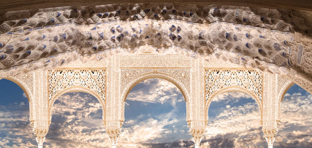 Arches in Islam (Moorish) style (against the background of a beautiful evening sky with clouds) in Alhambra, Granada, Spainの写真素材