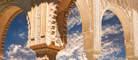 Arches in Islamic (Moorish) style (against the background of a beautiful evening sky with clouds) in Alhambra, Granada, Spainの写真素材