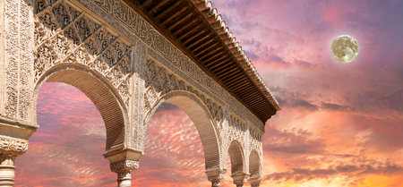 Arches in Islamic (Moorish) style (against the sunset with the super moon) in Alhambra, Granada,...