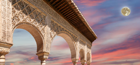Arches in Islamic (Moorish) style (against the sunset with the super moon) in Alhambra, Granada,...