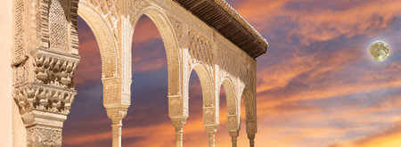 Arches in Islamic (Moorish) style (against the sunset with the super moon) in Alhambra, Granada,...