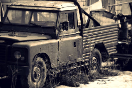 Old car on scrap heap covered with grass