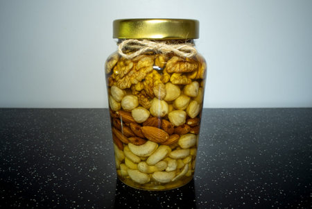 A jar of honey and nuts is on the table. Glass jar with natural and vegetarian healthy food