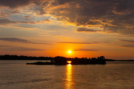 Sunset over the river and the reflection of the light of the Sun on the water, beautiful clouds over the forest in the distance. Dnieper river in Ukraineの写真素材