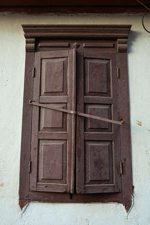 Old closed window with wooden shutters outside the houseの写真素材