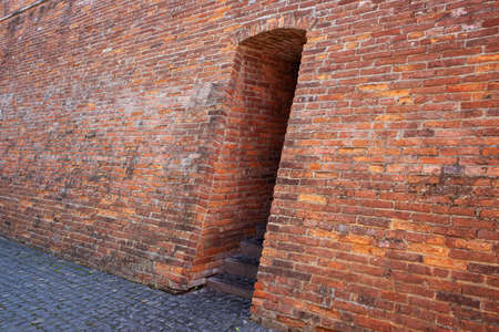 Doorway in an old brick wall and stone paving on the sidewalkの写真素材