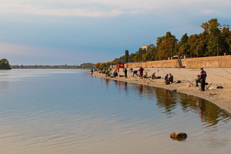 Kremenchuk city, Ukraine - September 26, 2022: Fishermen on the city beach on the banks of the Dnieper river. autumn sunny eveningのeditorial素材