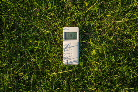 The device radiometer dosimeter lies on the green grass. Measurement of the level of ionizing radiationの写真素材