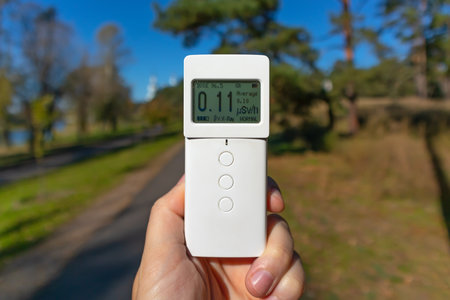 Radiometer dosimeter in hand outdoors. Measurement of ionizing radiation. Investigation of the terrain with the help of special measuring equipment. Modern problem of ecology - radの写真素材