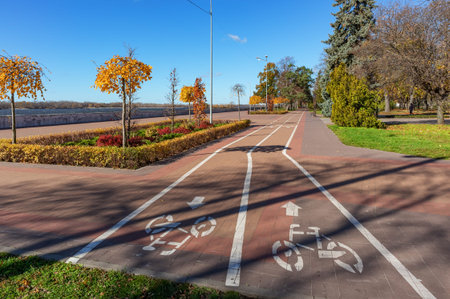 Bicycle path in the city garden along the river embankment on a sunny autumn day