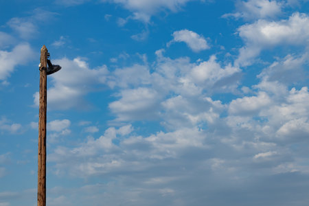An old wooden lamppost against a blue sky with white clouds. Free space for textの写真素材