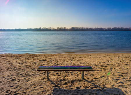 A wooden bench without people on the river bank on a sunny day. Beach on Dnerp river in Kremenchuk cityの写真素材
