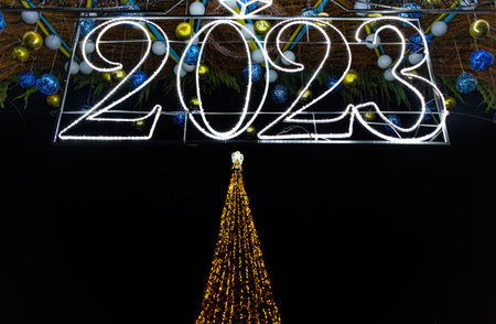 2023 numbers and Christmas tree outdoors at night. New Year and Christmas decorations in the form of balls, garlands and lights on a black backgroundの写真素材