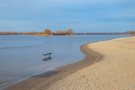 The water level in the Dnieper river has risenn. A wooden bench on the field stands in the water....