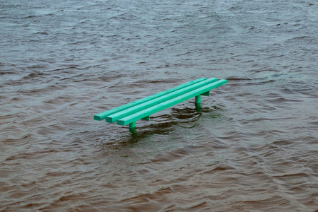 The bench is in the water. Beach or park floodedの写真素材