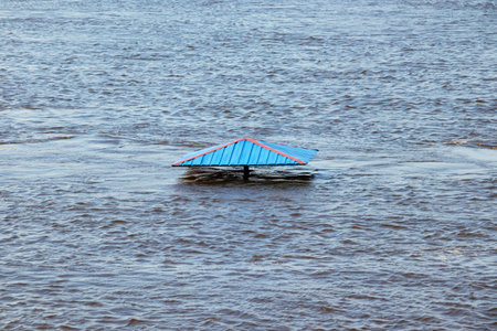 The beach is flooded with water in the springtime, an iron umbrella and waves on the surface of the water. Kremenchuk city, Ukraineの写真素材