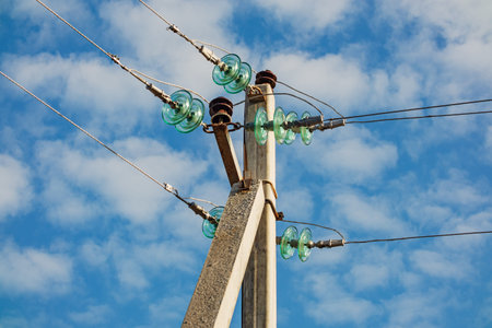 High-voltage electric transmission line with wires and insulators on a concrete pole close-up on a...