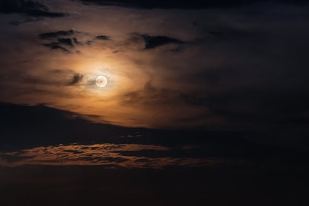 Full Moon surrounded by clouds in the night sky. Moonlight on a cloudy nightの写真素材