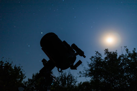 Silhouette of a telescope against the background of the night starry sky. Astronomical optical...