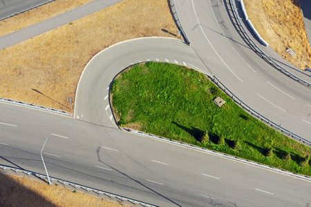 Aerial view of the turning of asphalt roads with white markings, metal fences and signsの写真素材