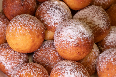 Dough balls sprinkled with powdered sugar are ready to eat. Food deep fried in oil