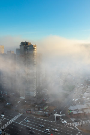 Dense fog in the city with multi-story building and roads, aerial view from aboveの写真素材