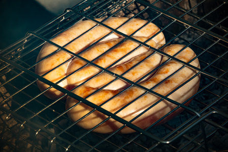 Chicken sausage is fried on the grill. Sausages in a metal grate are cooked over coalsの写真素材