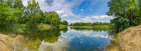 Panoramic view of the lake with deciduous trees on the banks. Landscape with picturesque nature...