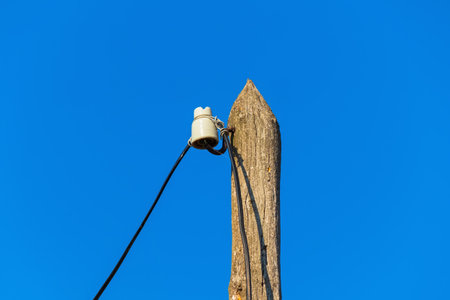 Wire and ceramic insulator on wooden poles. Blue clear sky on sunny dayの写真素材