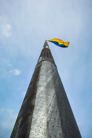 Large and tall flagpole with the flag of Ukraine. Directly under the National symbol of Ukrainians against the blue sky. View from the bottom upの写真素材