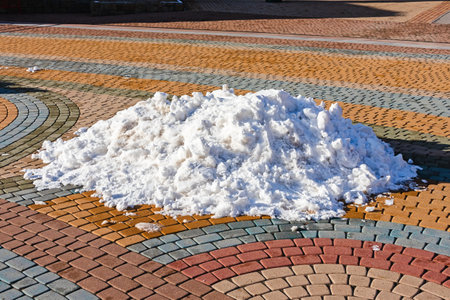 The last snow in the city. A pile of snow on the tiles melts under the spring sun. The end of winter in the cityの写真素材