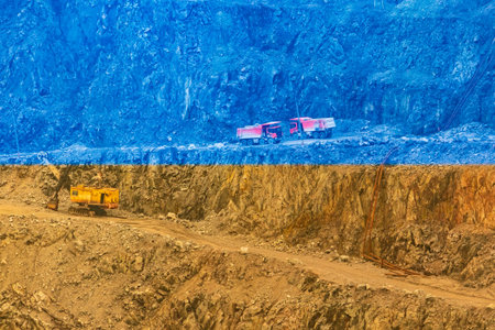 Open pit mining of mineral resources. Quarry dump trucks and an excavator on a slope
